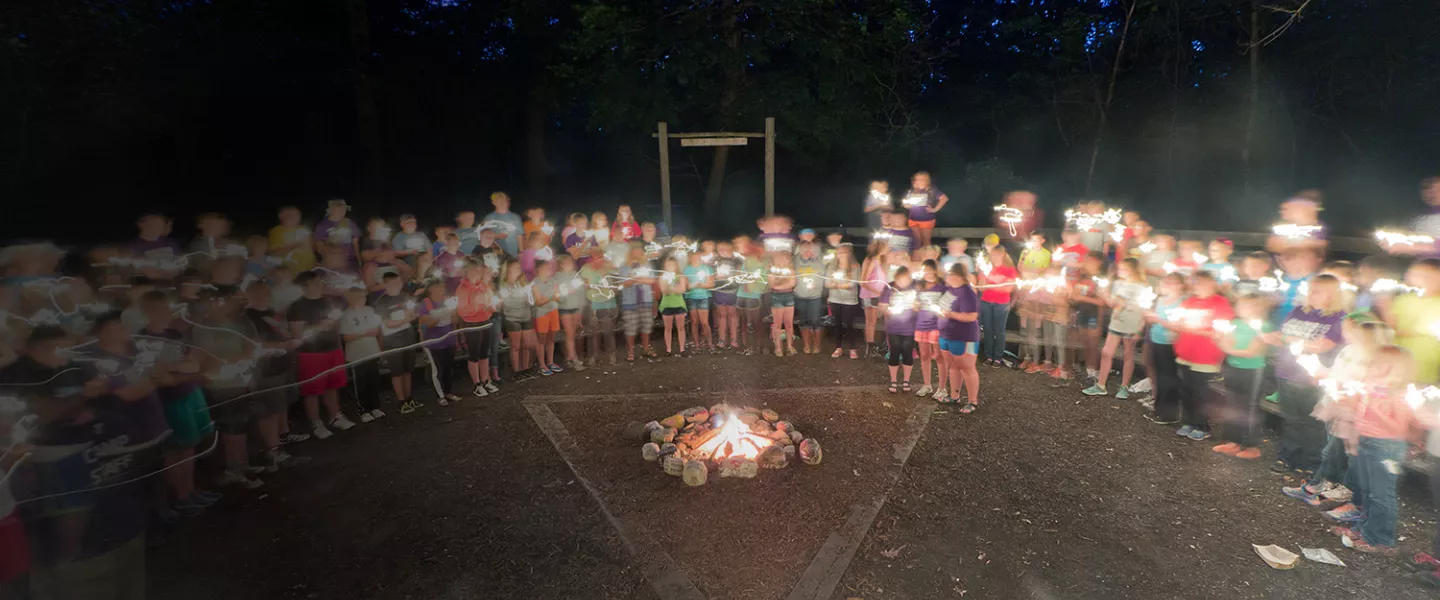 campers and staff around a campfire