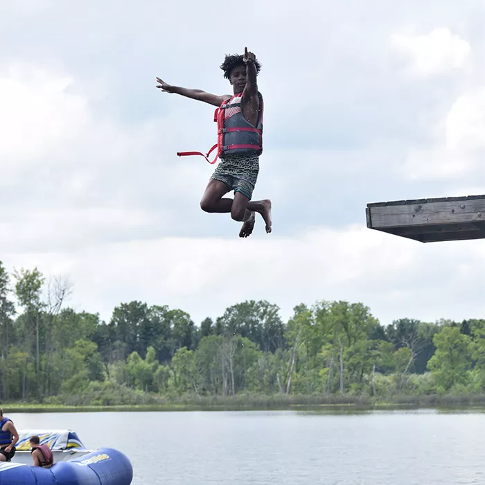 Camper jumping off high dive into the lake