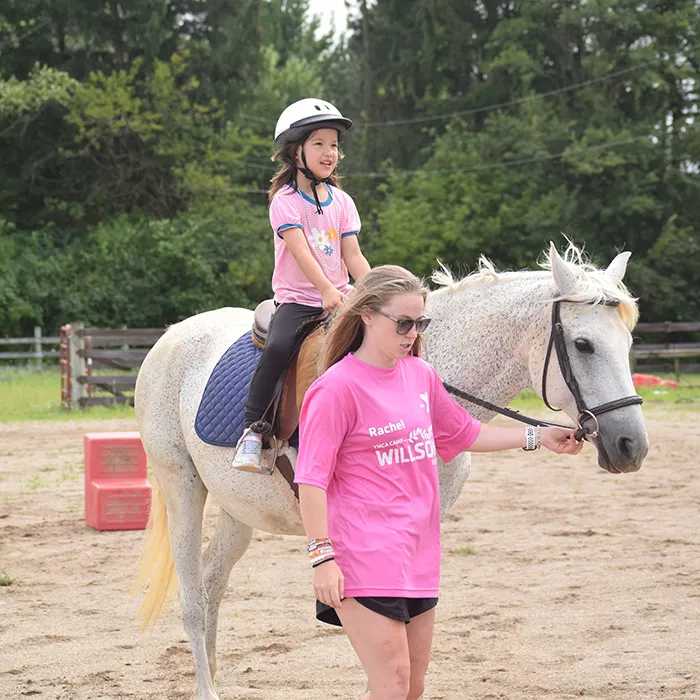 Camper riding a horse with staff walking along