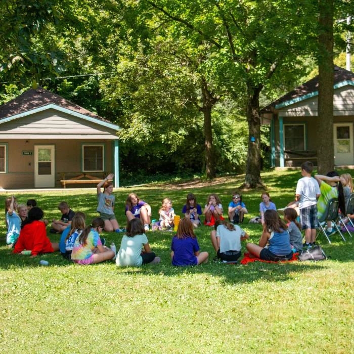 Campers sitting in a circle near cabins