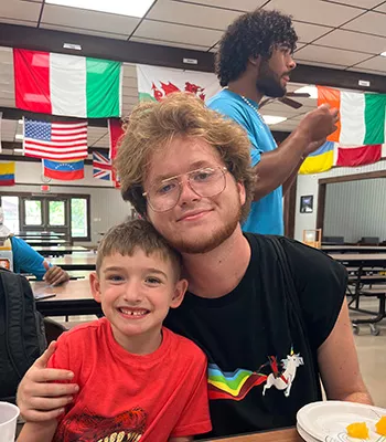 camper and counselor sitting at table in dining table