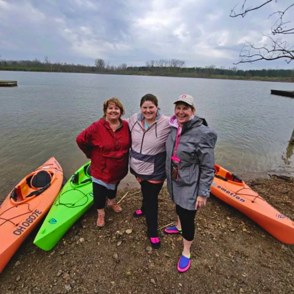 Three adult campers posing in front of the lake