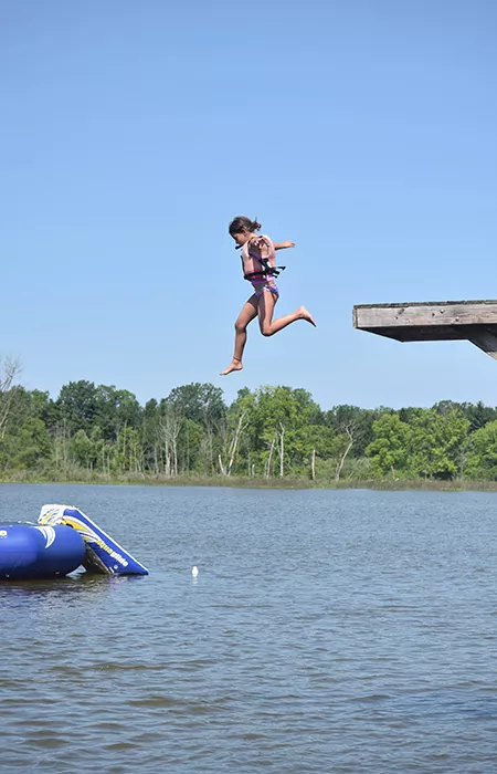 camper jumping off high jump into the water